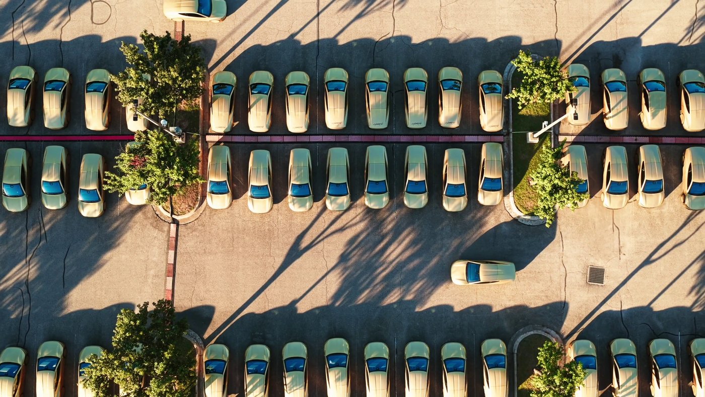 An aerial view of rows of gold Tesla Cybercabs parked in a lot, from Tesla's Robotaxi fleet update video