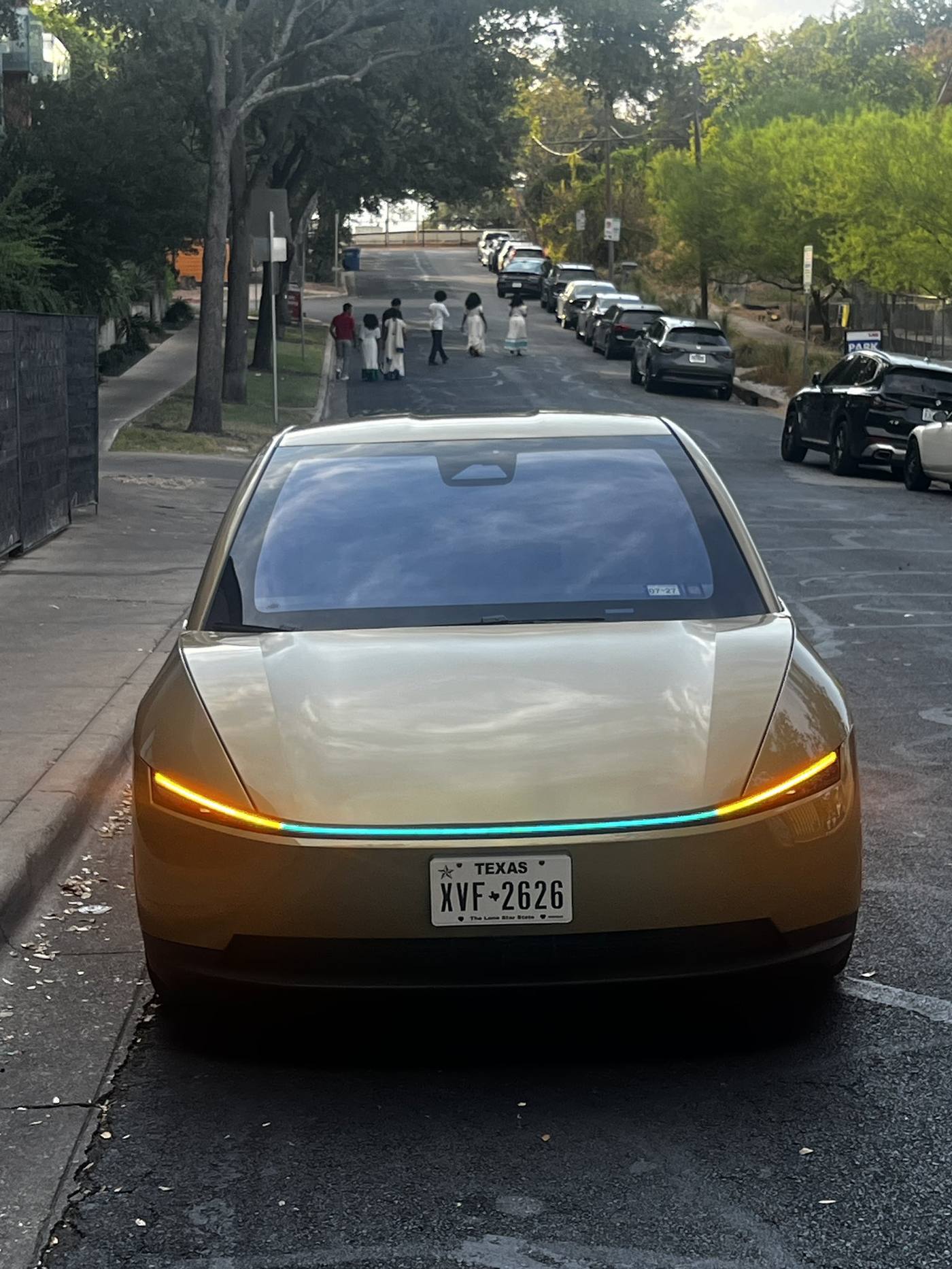 Gold Cybercab on an Austin residential street with its light bar lit.