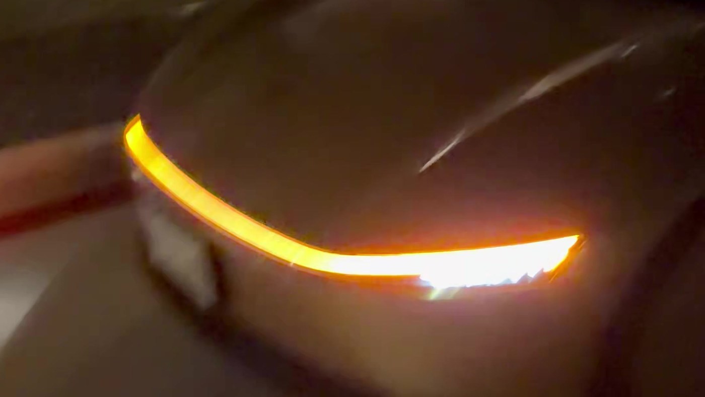 The light bar of a gold Tesla Cybercab glowing in the dark as the car arrives for a 12 a.m. pickup in the Austin area