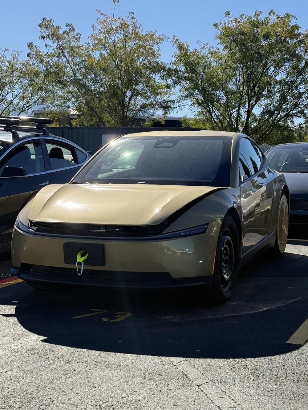 The Cybercab in the Tesla Service Center lot in Salt Lake City on Saturday, with a black steel front wheel and a green strap on its front plate mount. Image via @TeslaZoa / X