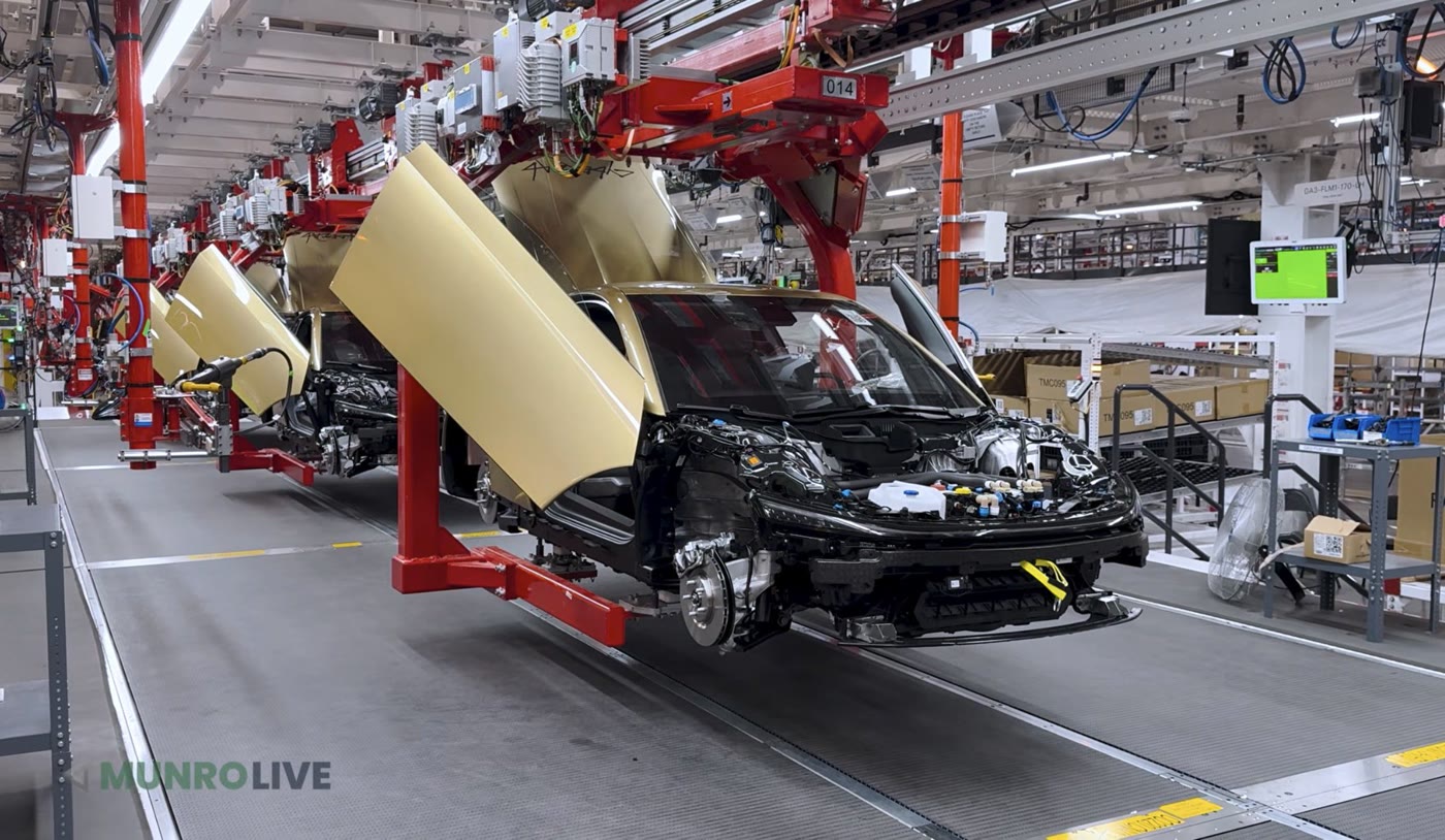 Gold Tesla Cybercabs with their doors raised moving along an automated production line