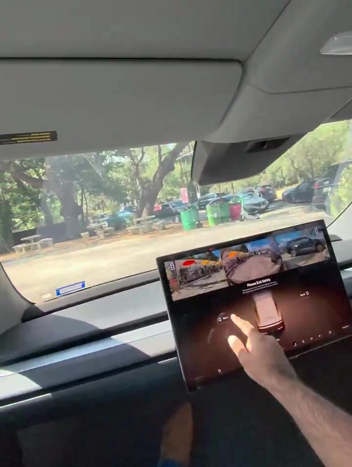 Cybercab cabin screen showing Please Exit Safely and Hold to Override while a rider points at the Open control