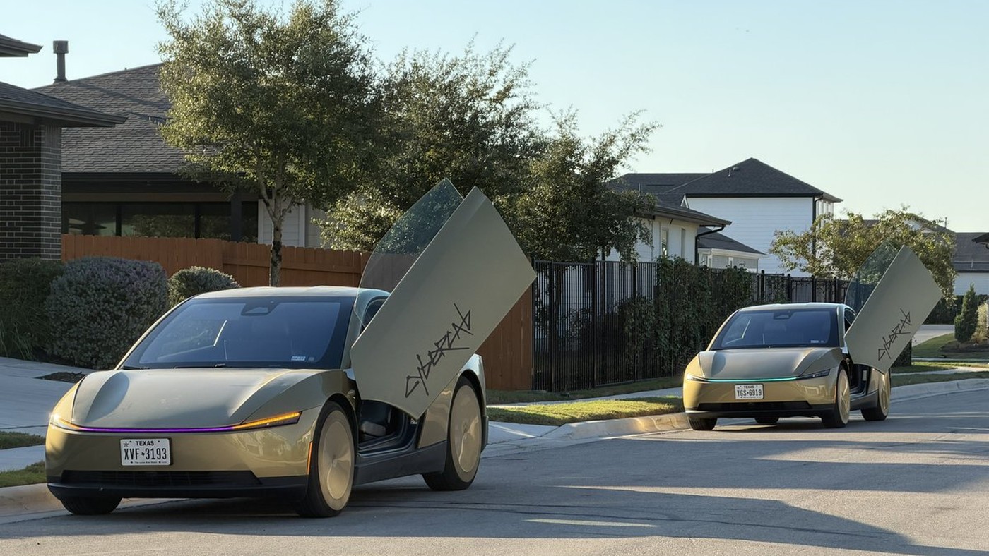 Two gold Tesla Cybercabs with butterfly doors open on a sunny residential street in Austin, Texas plates visible