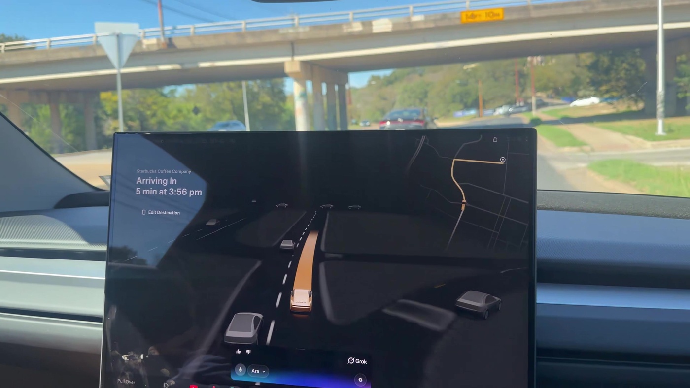 Tesla Cybercab cabin screen showing an active Grok bot interface during a daytime Robotaxi ride to Starbucks