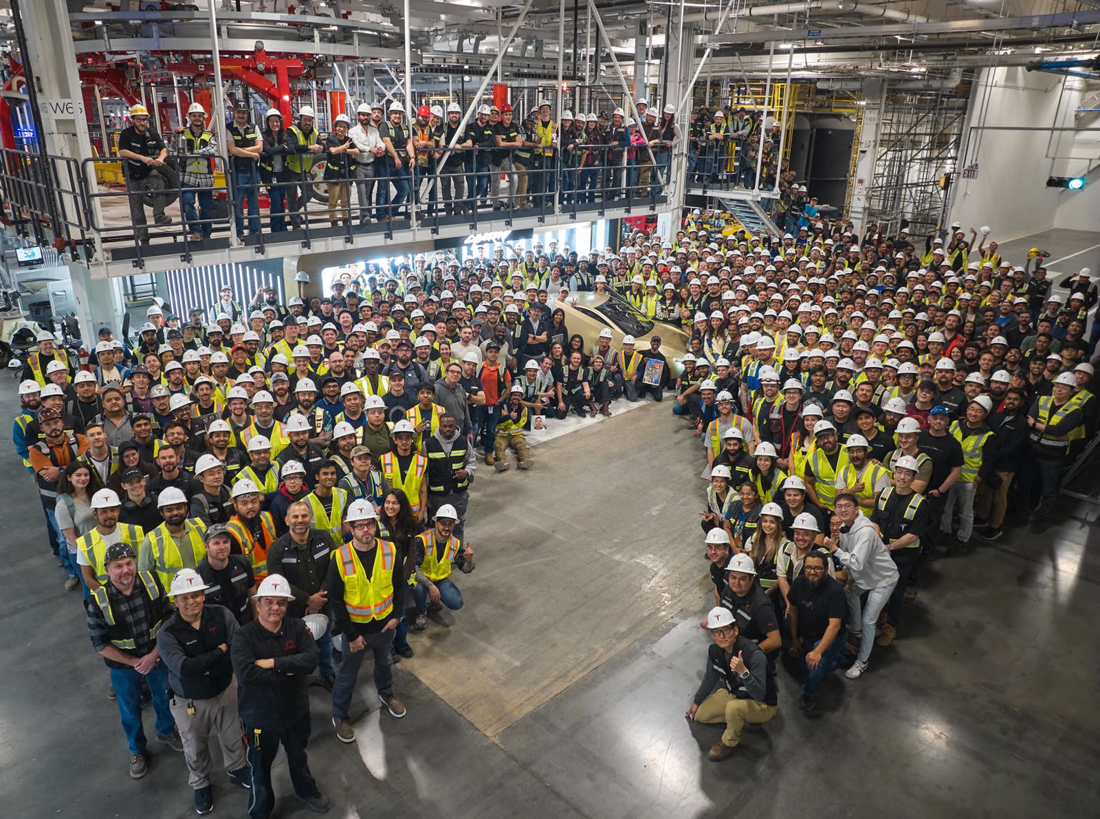 Tesla workers in safety vests surrounding the first production Cybercab at Gigafactory Texas