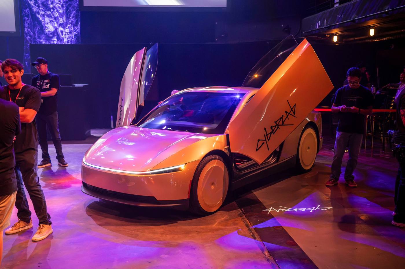 Gold Cybercab on a Hong Kong Asia-tour display floor with doors raised.