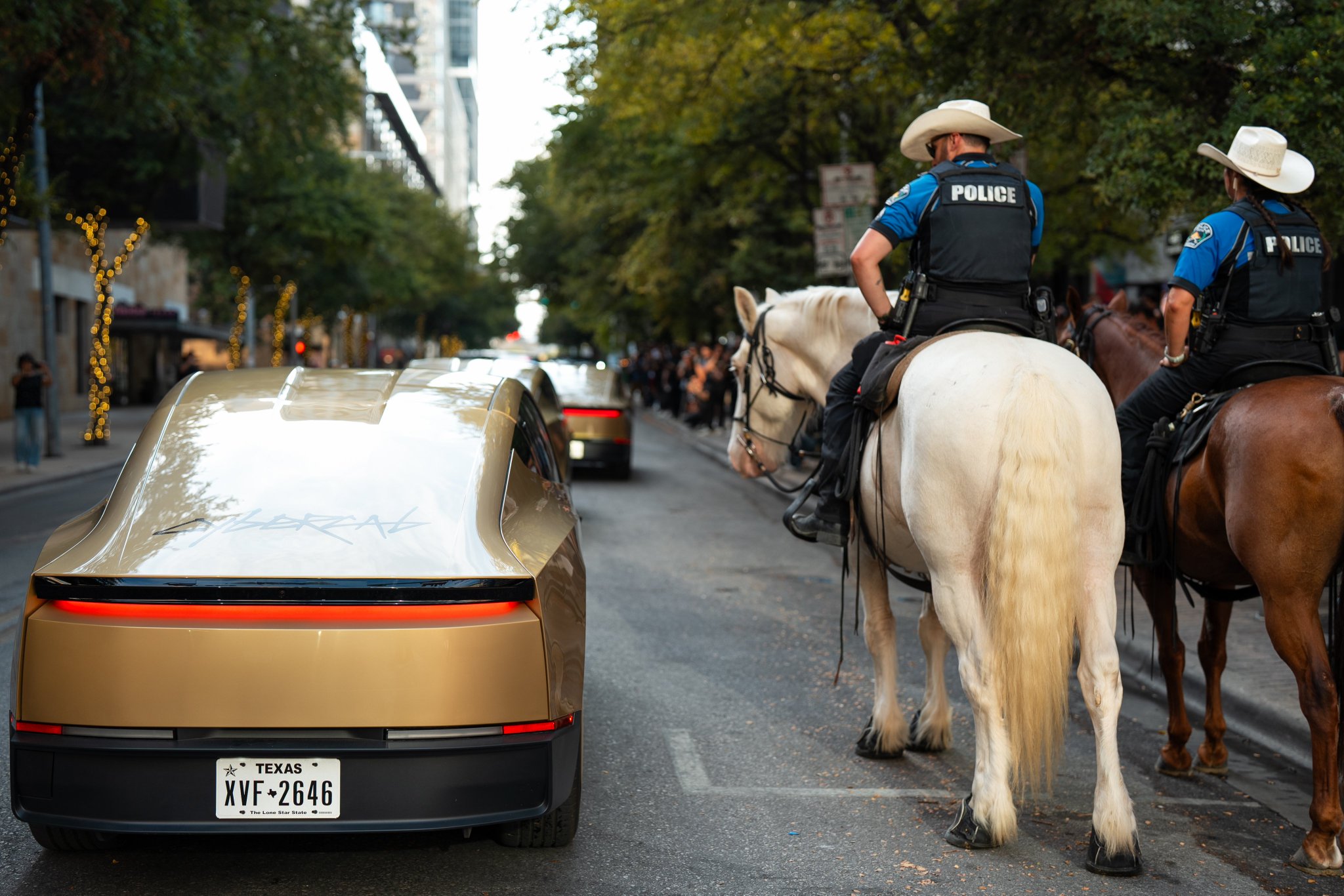 Cybercab XVF-2646 on an Austin street beside mounted police officers