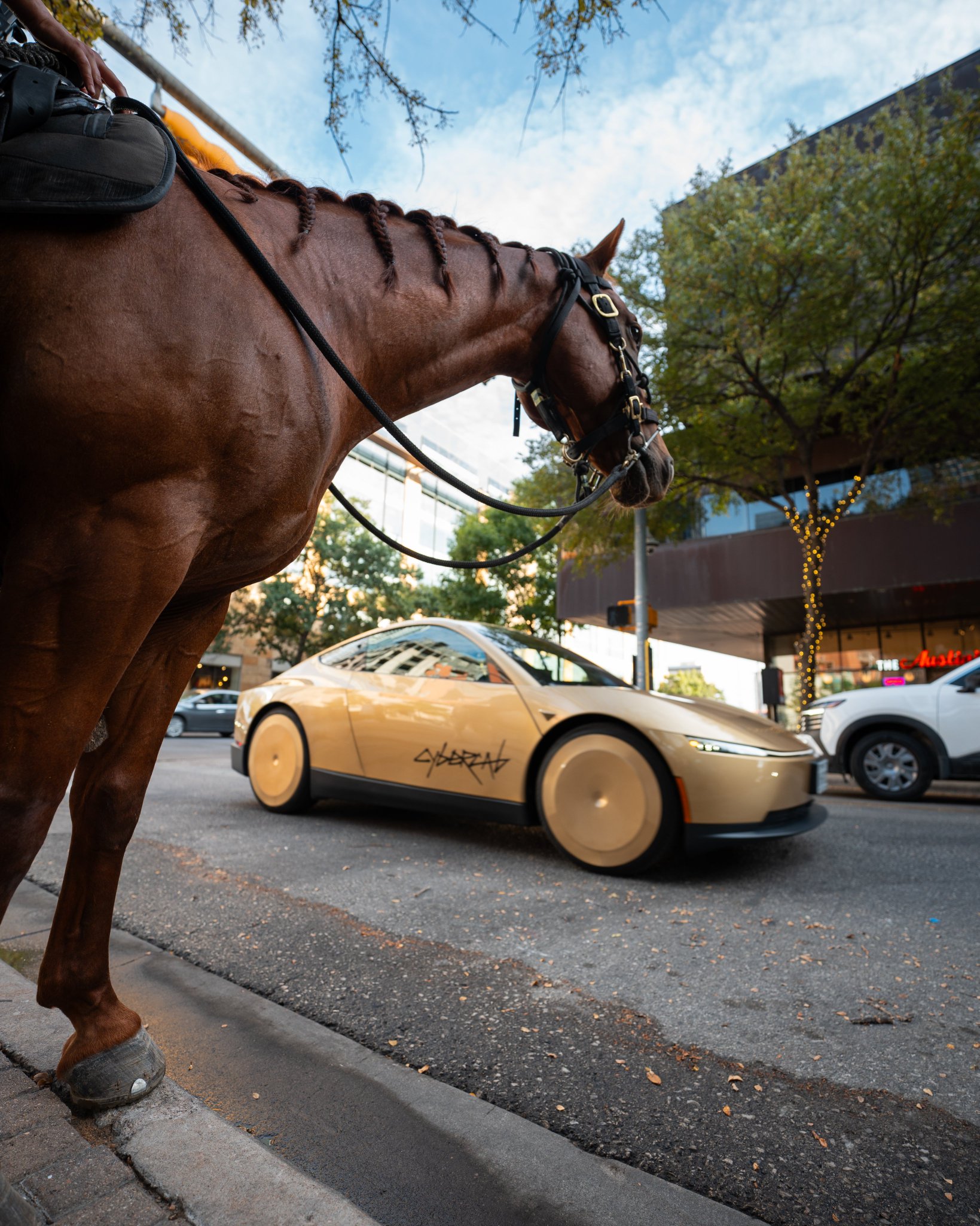 A mounted police horse in the foreground as a gold Cybercab rolls past