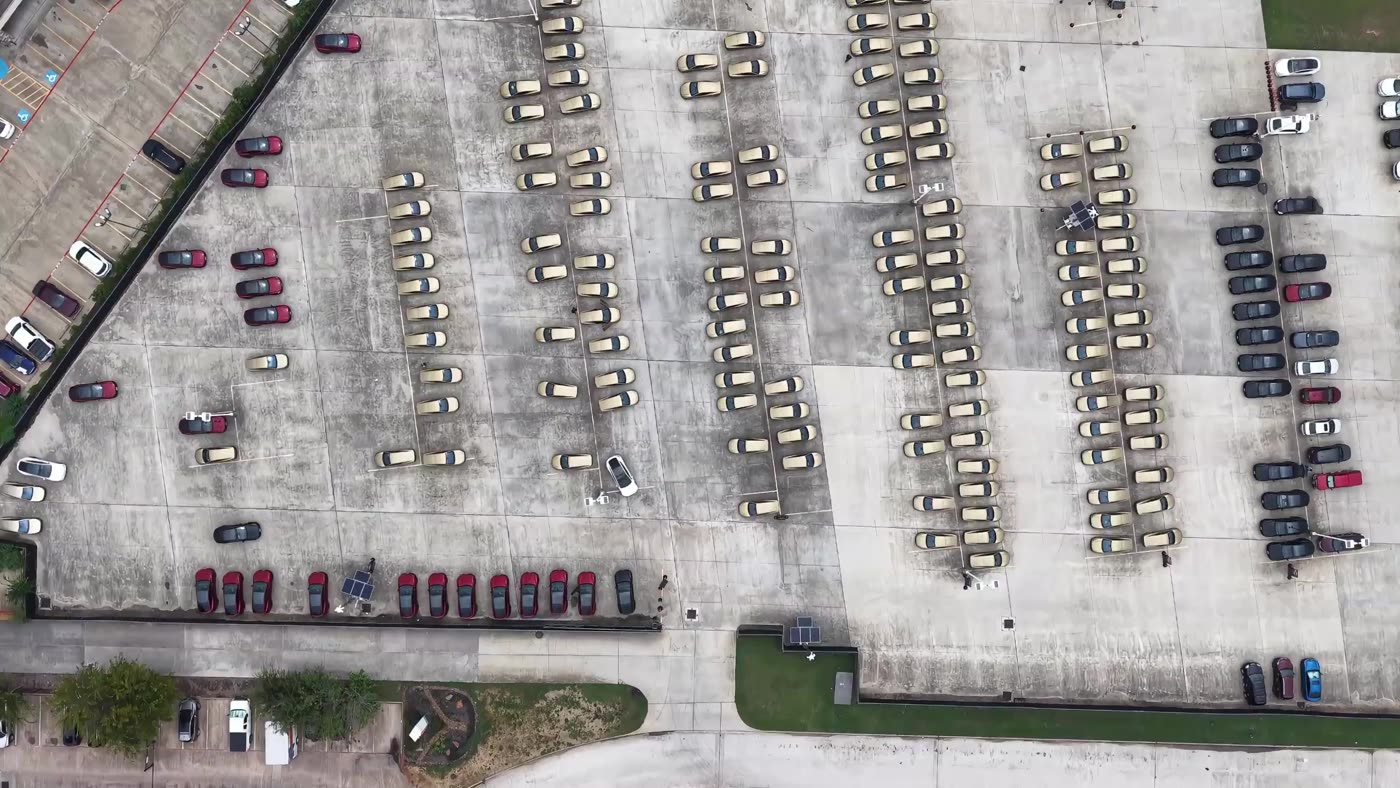 Aerial drone view of rows of gold Tesla Cybercabs parked in Tesla's Houston fleet lot