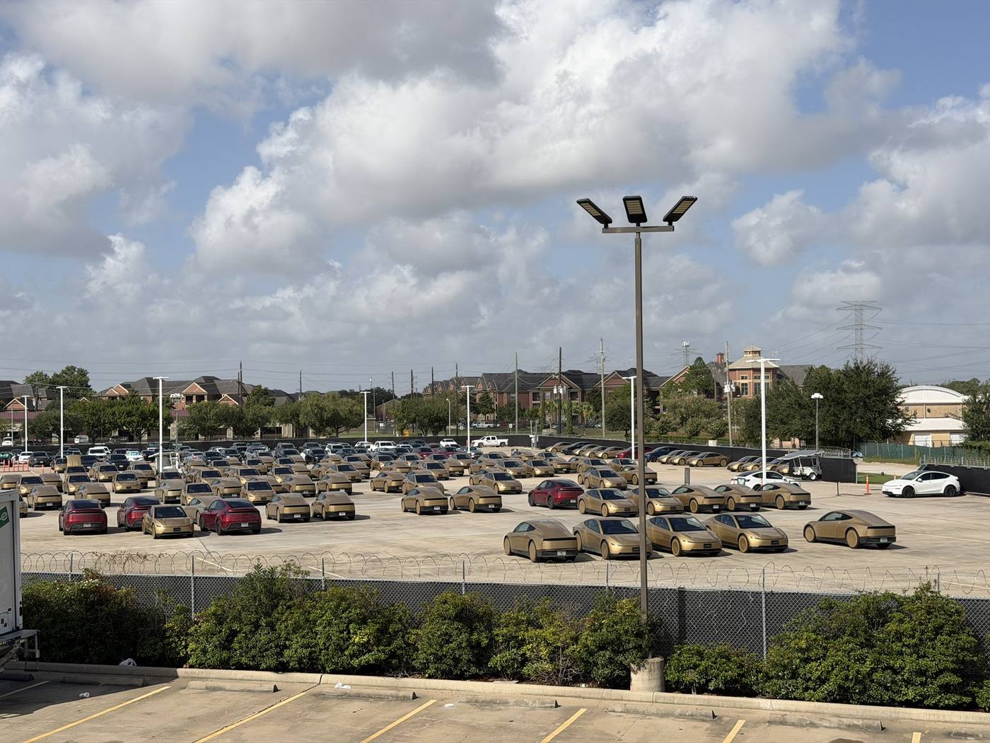 Elevated view of gold Cybercabs in Houston's Robotaxi fleet lot.