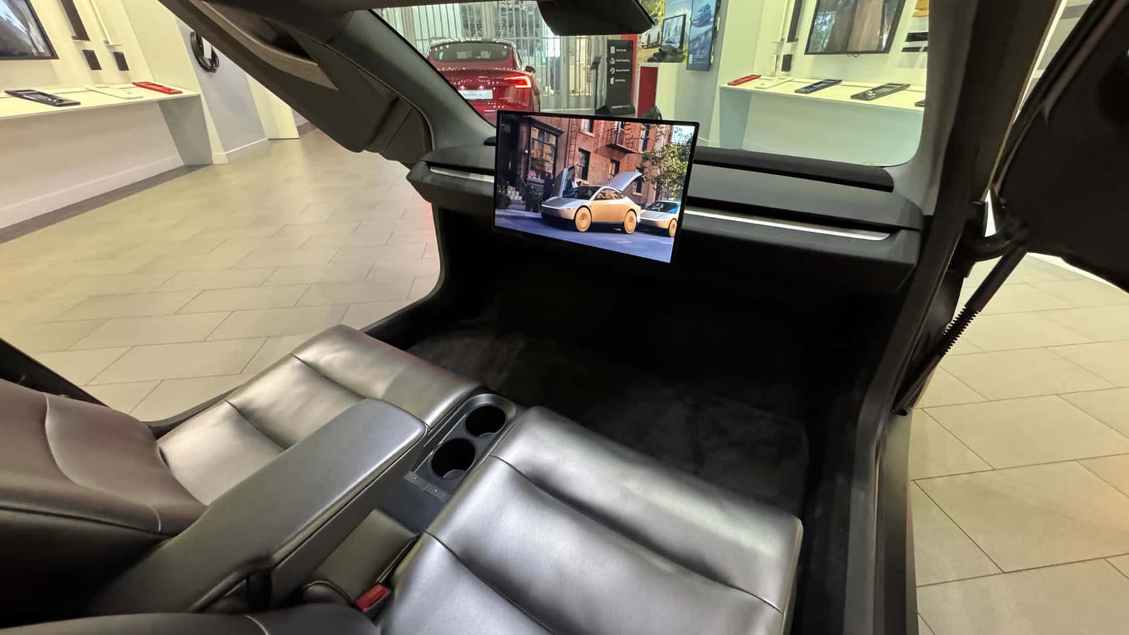 Cybercab interior with two black lounge seats, cupholders, and a landscape screen — no steering wheel