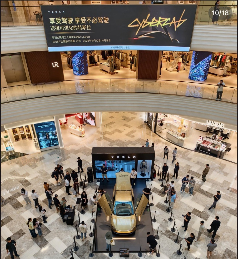 The gold Cybercab with butterfly doors raised at Suzhou MixC World, under a banner for Tesla's 2026 national static tour, Oct. 10 to Oct. 18. Photo via @tslaming / X