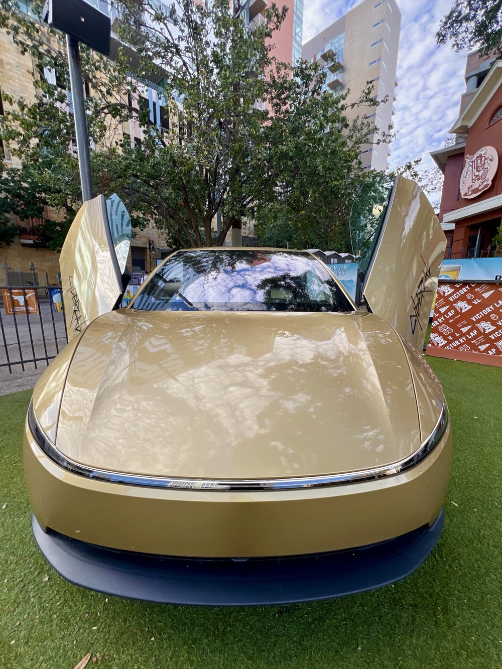 A Cybercab with its doors raised on the turf at Victory Lap, near the University of Texas campus in Austin, on Saturday. Image via @JoshWest247 / X