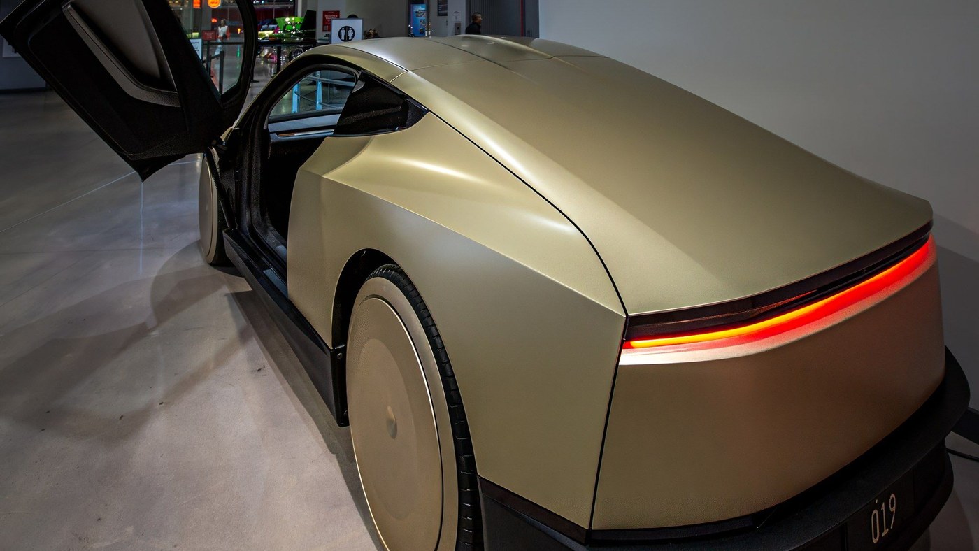 A gold Tesla Cybercab on display indoors with its door raised