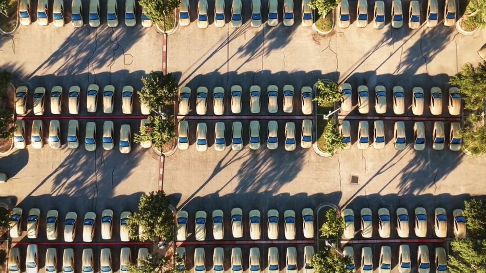 Aerial view of rows of gold Cybercabs in a Texas staging lot, posted with Tesla's active-fleet confirmation. Photo via @SawyerMerritt / X
