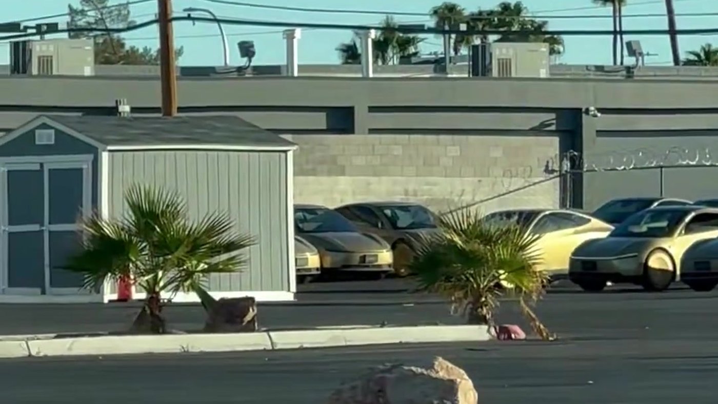 Gold Tesla Cybercabs parked in a Las Vegas lot behind a small shed and palm trees