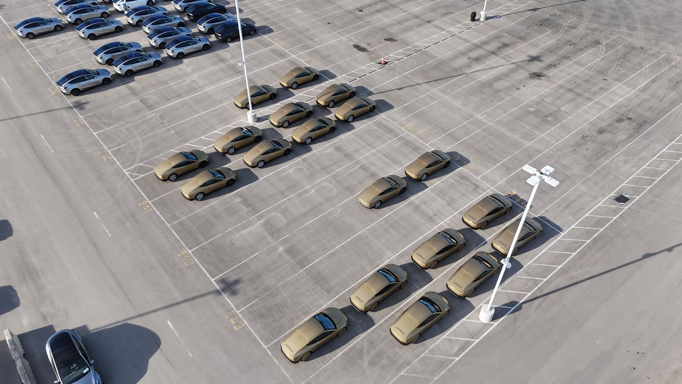 Rows of gold Tesla Cybercabs parked in a lot at Giga Texas, seen from a drone