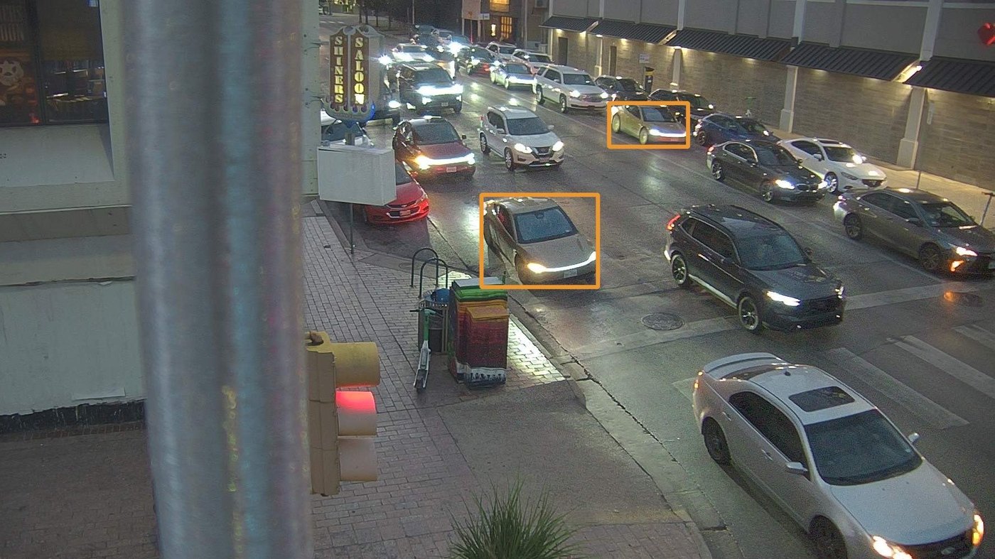 Two Cybercabs, boxed in orange, in evening traffic in downtown Austin, seen on a city traffic camera. Image via @RobotaxiRadar / X