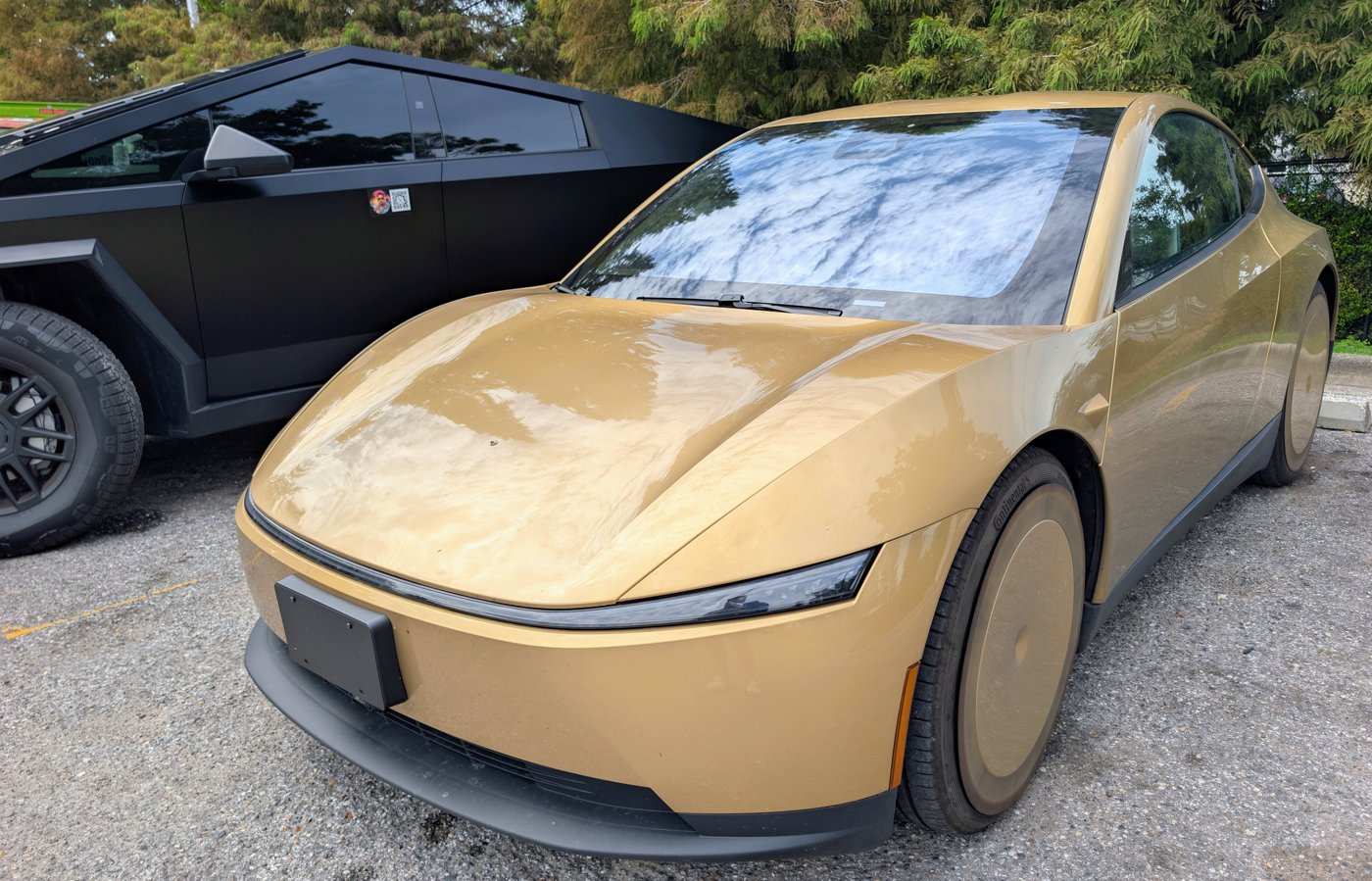 A gold Tesla Cybercab parked beside a black Cybertruck, in a photo shared on X by a Tampa Robotaxi rider