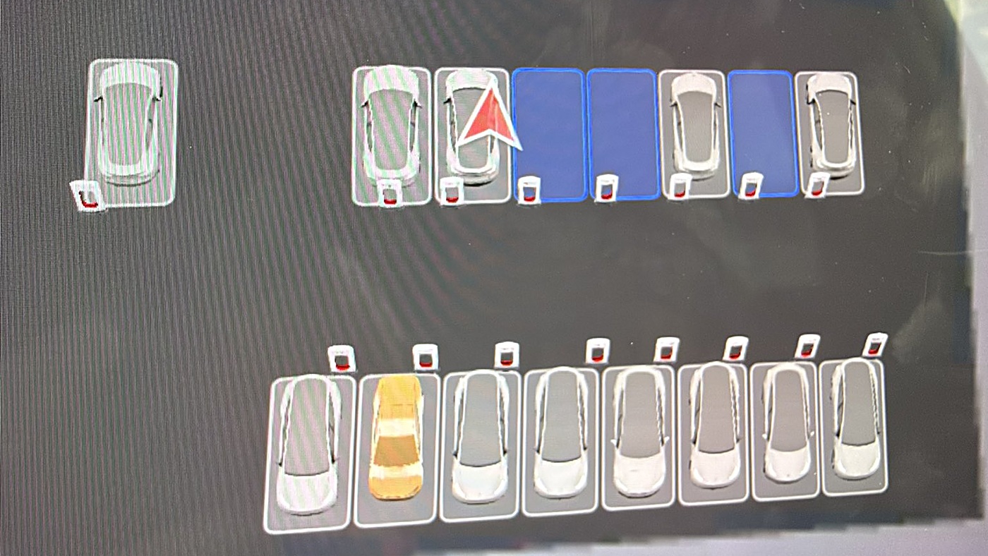A Tesla touchscreen Supercharger site map showing rows of white cars in charging stalls, with one car drawn in gold
