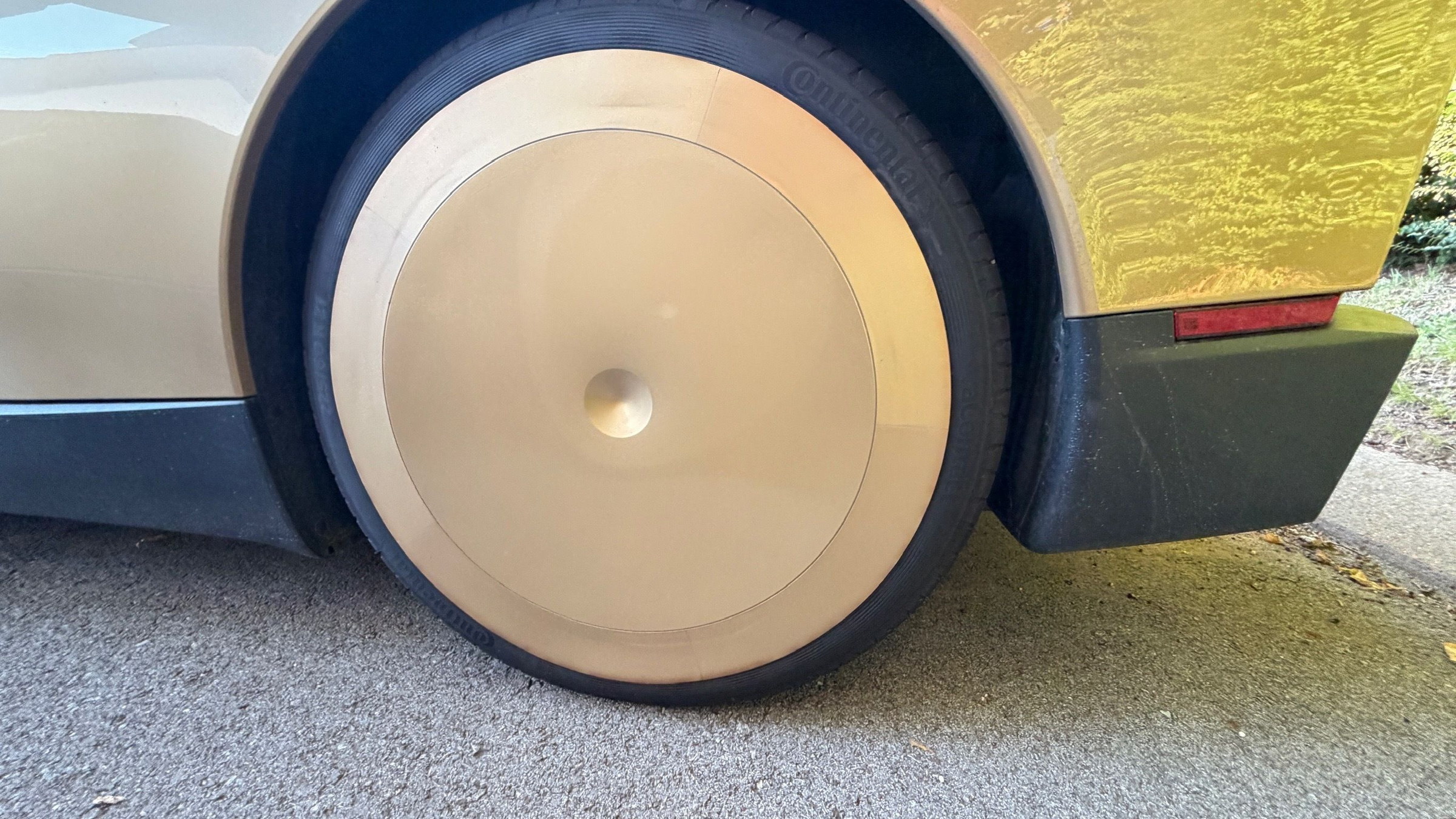 Gold Cybercab aero wheel cover in place on a Continental tire, showing the rubber outer ring flush with the sidewall